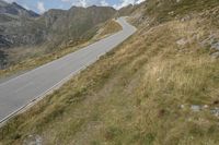 a large motorcycle is driving down the winding country road through the mountains along the grassy hillside, in front of mountains