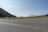 a motorcycle parked on a small mountain side road near mountains with no cars driving on it