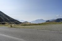 a motorcycle parked on a small mountain side road near mountains with no cars driving on it