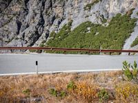 a single speed car driving on the road in front of mountains and a large rocky cliff