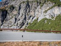 a single speed car driving on the road in front of mountains and a large rocky cliff