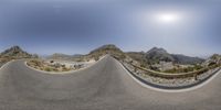 a curved road is shown through a fish eye lens with the sun shining through it