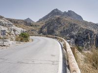 a mountain road winding through the mountains into the distance, with the mountains surrounding it