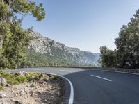 there is a large mountain with a road in the middle of it and a motorcycle that has been parked on the side of the street