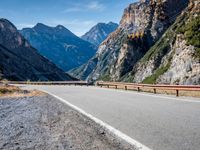 a road near mountains with cars going through it on a clear day in italy by a cliff