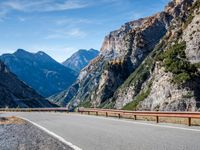 a road near mountains with cars going through it on a clear day in italy by a cliff
