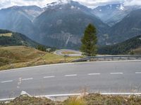 a curvy road passing through a mountainous valley with trees and grass on the sides