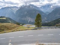 a curvy road passing through a mountainous valley with trees and grass on the sides