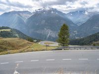 a curvy road passing through a mountainous valley with trees and grass on the sides