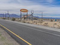 a road and sign are set on the side of a road with mountains in the distance