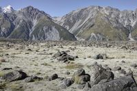 an expanse with rocks, grass and mountains in the background that appear to be about 50 percent in height of mountains