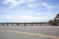 the road is very scenic by the ocean, and has an ocean and blue sky