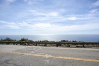 the road is very scenic by the ocean, and has an ocean and blue sky