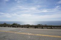 the road is very scenic by the ocean, and has an ocean and blue sky