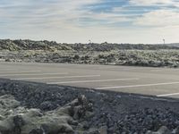 empty parking lot with white lines and rocky terrain in the background, with mountains in the distance