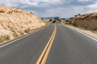 an empty road runs through the sand and dirt on the hill side with rocks on both sides of it