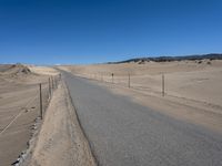 a paved beach with a fence in front of it and the ocean in the distance