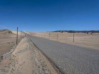 a paved beach with a fence in front of it and the ocean in the distance