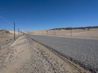 a paved beach with a fence in front of it and the ocean in the distance