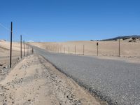 a paved beach with a fence in front of it and the ocean in the distance