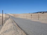 a paved beach with a fence in front of it and the ocean in the distance