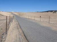 a paved beach with a fence in front of it and the ocean in the distance