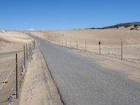 a paved beach with a fence in front of it and the ocean in the distance