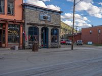 a red fire hydrant sitting in front of an old store window and building next to an open air field