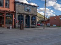 a red fire hydrant sitting in front of an old store window and building next to an open air field