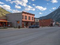 a red fire hydrant sitting in front of an old store window and building next to an open air field