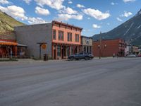 a red fire hydrant sitting in front of an old store window and building next to an open air field