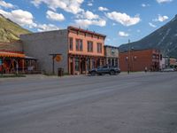 a red fire hydrant sitting in front of an old store window and building next to an open air field