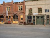 a red fire hydrant sitting in front of an old store window and building next to an open air field