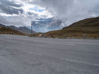 the open road on the mountain with snow capped mountains in the background near an empty highway