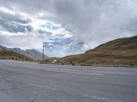 the open road on the mountain with snow capped mountains in the background near an empty highway