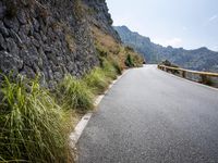 an empty road leading off into the distance along a mountainous ridge side in the mountains
