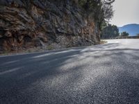 this is a curve in the road on the side of the mountain side with trees