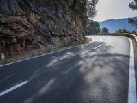 this is a curve in the road on the side of the mountain side with trees