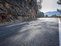 this is a curve in the road on the side of the mountain side with trees