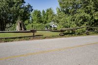 a split rail fence sits on the side of a road near a fence that has fallen across it