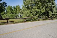 a split rail fence sits on the side of a road near a fence that has fallen across it