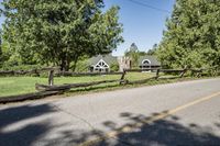 a split rail fence sits on the side of a road near a fence that has fallen across it