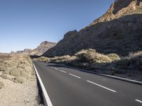 a long empty road winds through a mountain range at the center of a desert landscape