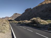 a long empty road winds through a mountain range at the center of a desert landscape