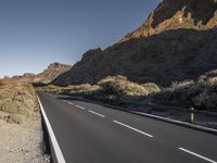 a long empty road winds through a mountain range at the center of a desert landscape