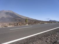 a road near the mountain side in the foggy sun day, and on the opposite bank are hills