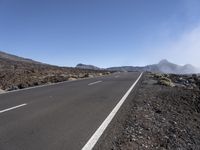 a road near the mountain side in the foggy sun day, and on the opposite bank are hills