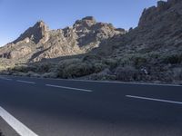 a long narrow highway with a curve down the side of it and a steep mountain behind it