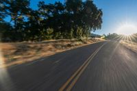 the image is from inside of a car going down the road in the sun rays