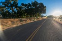 the image is from inside of a car going down the road in the sun rays